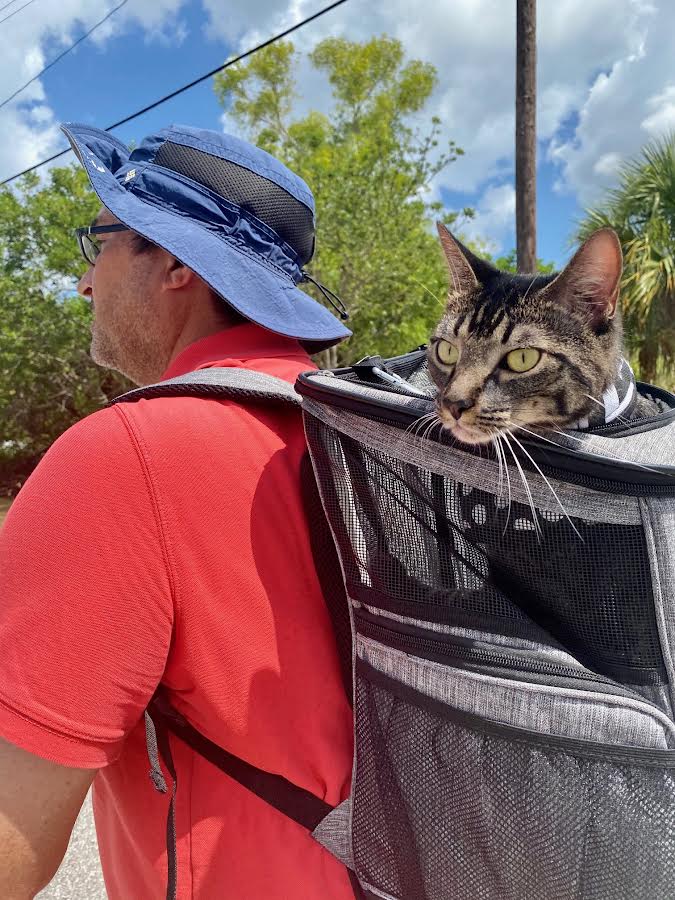 Man walking outdoors with a cat peeking out of a pet backpack — Father's Day at Marina Made It