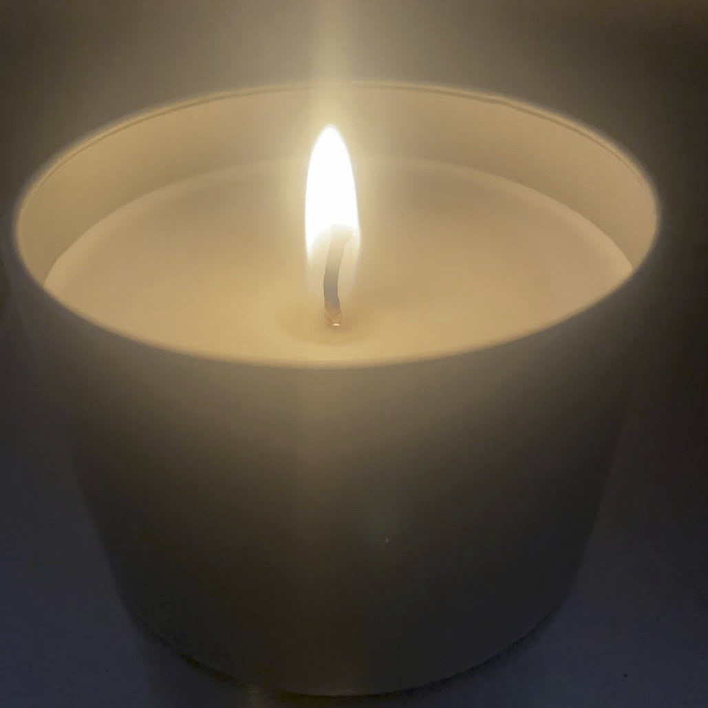 Candle in tin container with a soft glow on a dark background