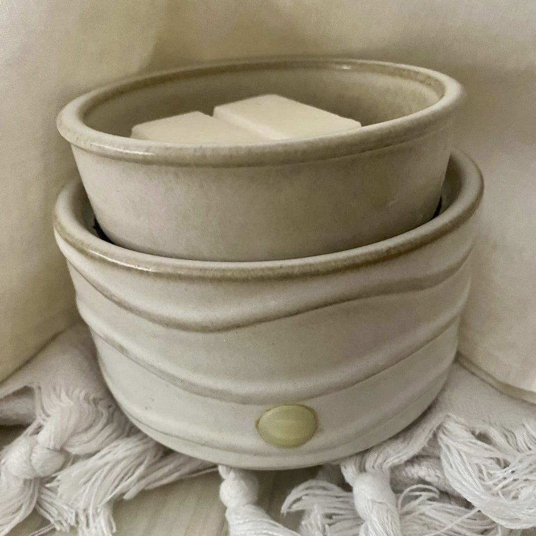 Stack of beige ceramic pots with a textured surface on a neutral background